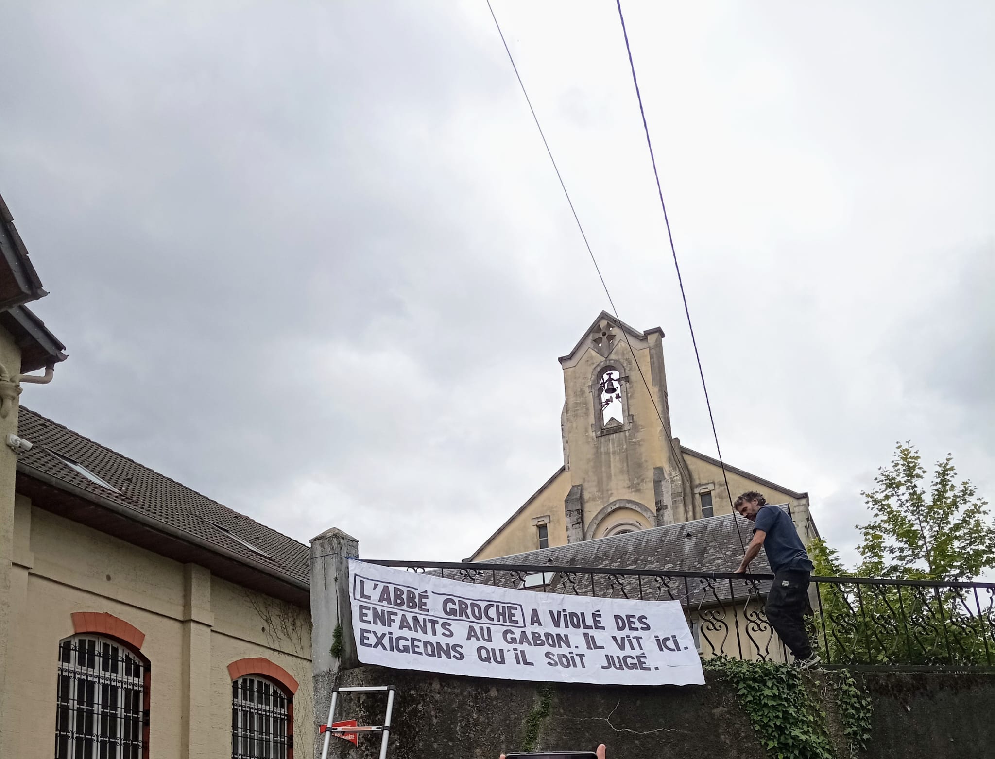 Banderole déployée devant la maison Saint Ignace de la Fraternité Saint Pie X à Lourdes : "L'abbé Griche a violé des enfants au Gabon. Il vit ici. Exigeons qu'il soit jugé."